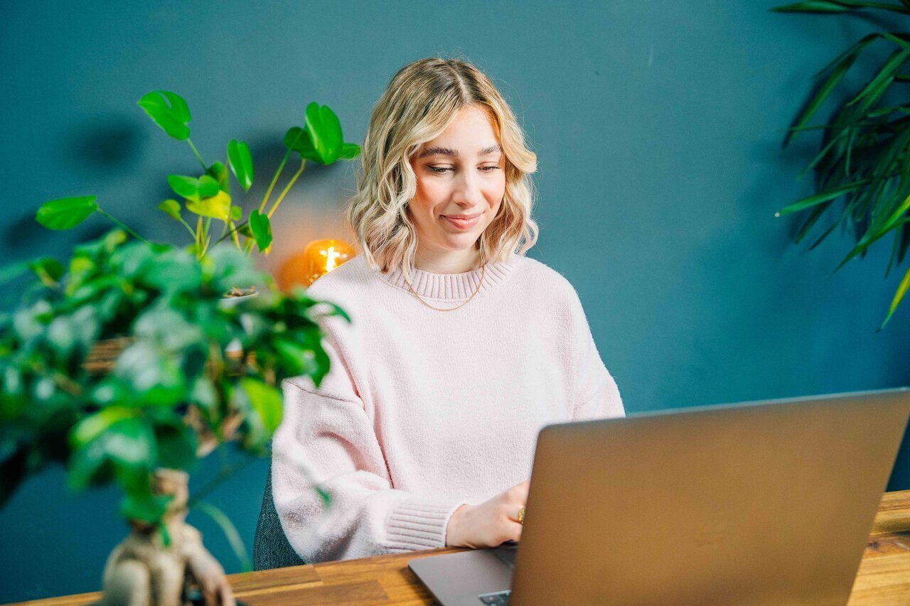 Woman with a laptop and plant with a smile on her face